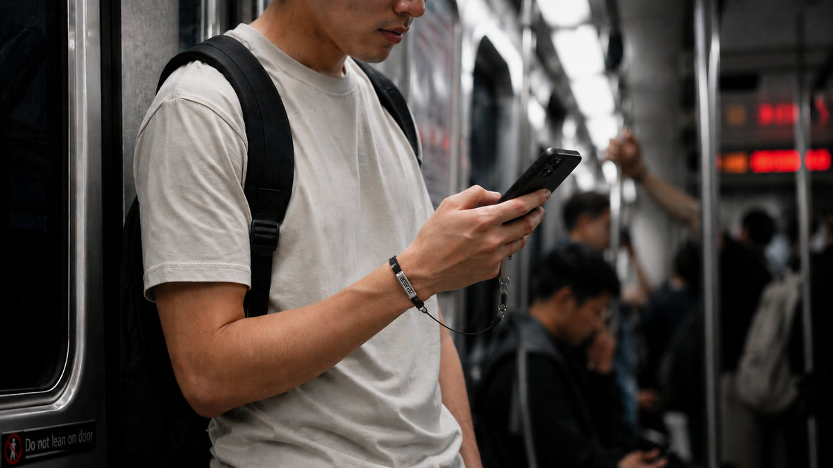Commuter using a phone one-handed with a PHLOOP bracelet phone holder tether on the wrist