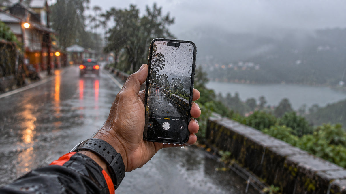 Phone held in a hand in heavy rain, the kind of moment phones get lost and need tracking